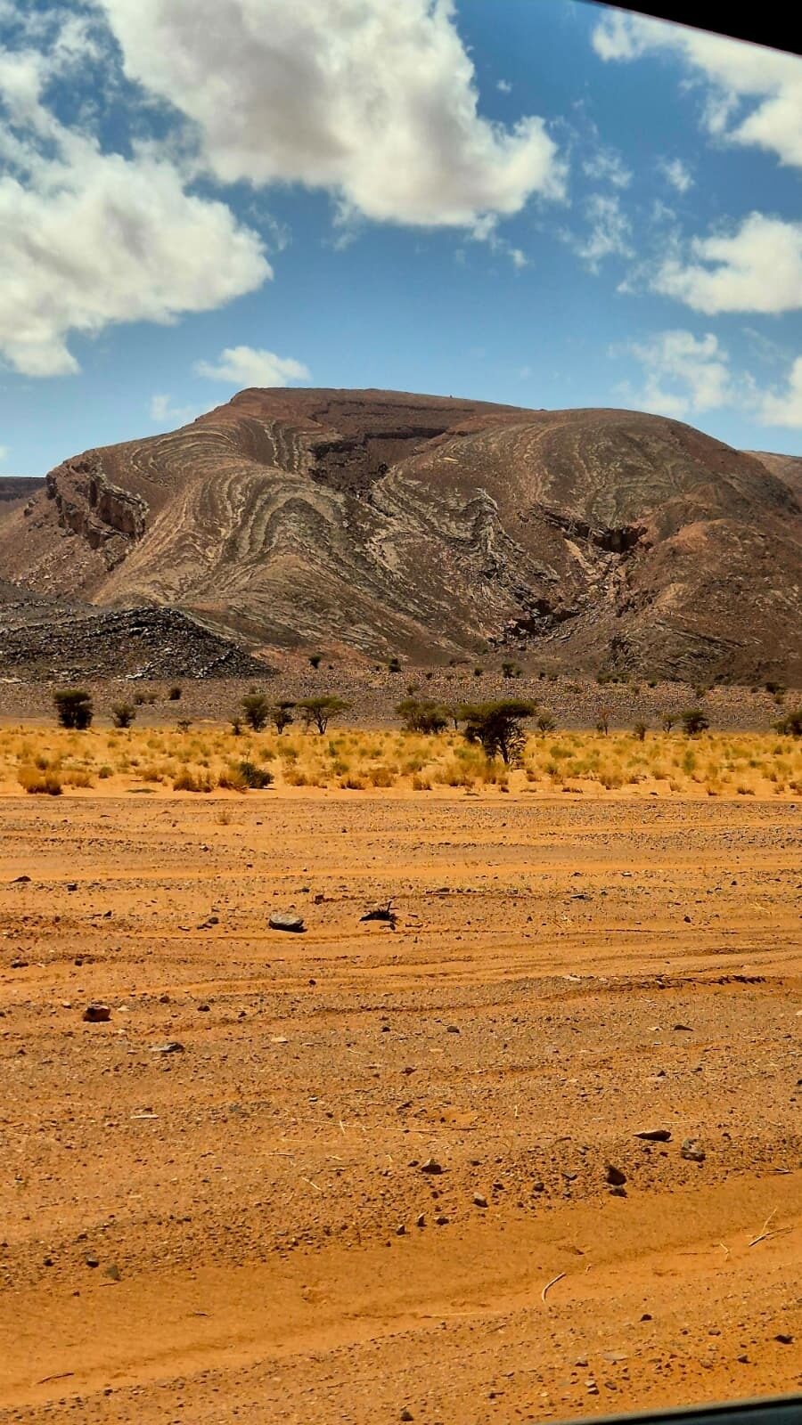Flat desert plain in front of a striped mountain